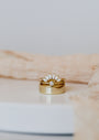 The Simple Stud Ring is an 18k gold plated stacking ring set featuring a central round cubic zirconia and a crown-like band with marquise-shaped stones, shown on a white surface with soft beige fabric in the background.