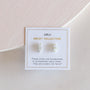 A pair of White Bar Druzy stone stud earrings, set in 18k gold plated sterling silver, come on a “JaxKelly Druzy Collection” card that reads: “These studs are handpicked to complement each other: they are sisters not twins.”.