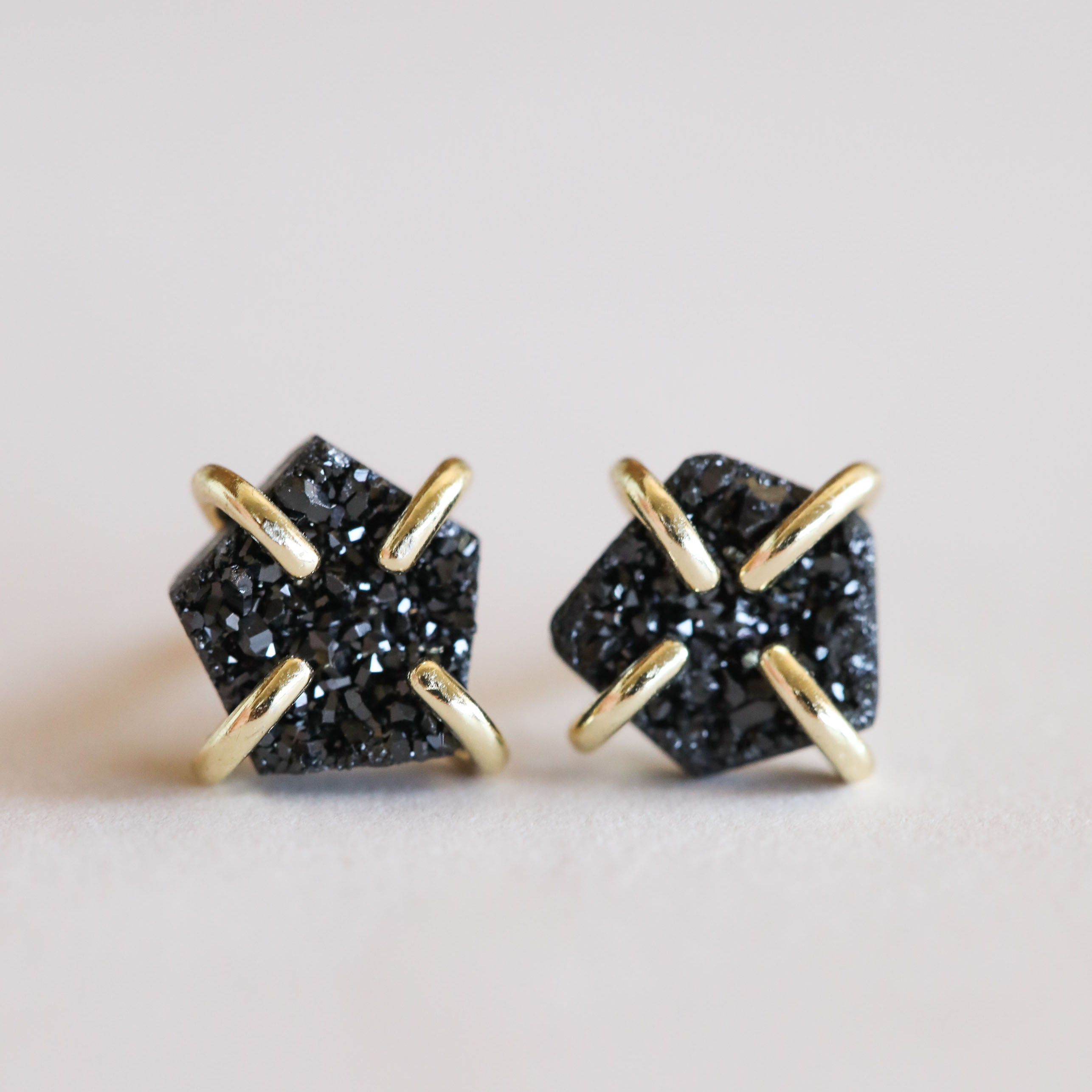Black Druzy Prong: Pentagon-shaped black natural druzy stone stud earrings set in gold prongs with 18k gold plating, shown on a light background.