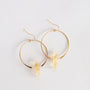 The JaxKelly Citrine Hoop - Success features gold hoops with clear citrine quartz pendants, shown on a white background. These hypoallergenic earrings offer everyday elegance and style.