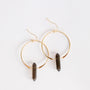 Displayed on a plain white background, the Smoky Quartz Hoop - Protection features gold hoops with a dark smoky quartz crystal pendant hanging from each earring.