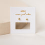 A pair of Gold Sphere Huggie earrings with sterling silver posts displayed on a white card featuring gold JAXKELLY wear good vibes text and a rectangular cutout below the earrings, set against a neutral background.