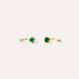 The Emerald CZ Huggie features delicate 18k gold plated huggie hoops, each set with a small, round emerald CZ stone in a four-prong setting, shown against a plain white background.