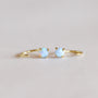 A pair of Fire Opal Huggie earrings, each set with a small round lab-grown fire opal held by four prongs, displayed on a light, neutral background.
