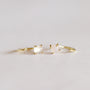 Two delicate gold rings with small white and pale pink gemstones are placed side by side on a soft, neutral background—perfectly complementing the elegant Rose Quartz Huggie earrings.