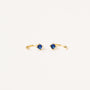 The Sapphire CZ Huggie features delicate gold open hoops with a single round blue cz stone at the center, shown on a plain white background.