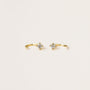 The White CZ Huggie is a pair of dainty gold-plated earrings, each featuring a small, round, clear gemstone at the center, displayed on a plain light background.