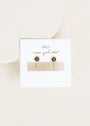 A pair of gold Sun Huggie earrings shaped like sunflowers with clear gemstone centers, displayed on a white JaxKelly card labeled "wear good vibes," set against a light neutral background.