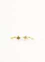 The Star Huggie is a delicate gold ring with two star-shaped ends, each set with a small gemstone, paired elegantly with 18k gold plated earrings and showcased on a plain white background.