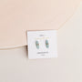 A pair of light blue Amazonite Mineral Point - Hope earrings with gold wire accents and sterling silver posts, displayed on a white card labeled “AMAZONITE hope” against a pale, neutral background.