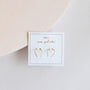 A pair of Minimalist Horseshoe 18k gold plated earrings, displayed on a white card with gold trim featuring the JAYKELLY brand and "wear good vibes" text, set against a light neutral background.