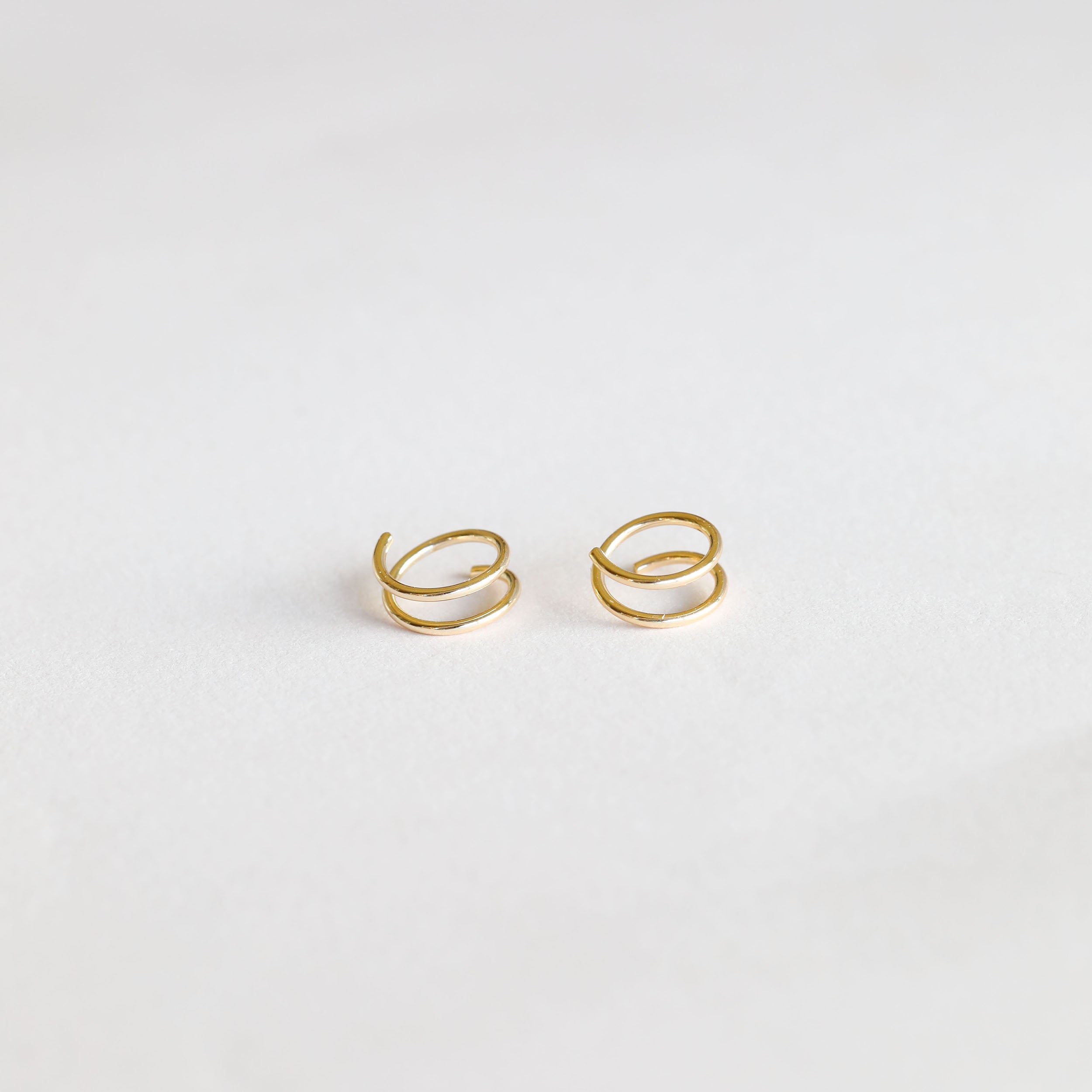 A pair of Minimalist Spiral earrings featuring a double spiral design with 18k gold plating, shown on a plain white background.