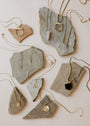 The Tiny Star Necklace, an 18k gold plated piece with a Cubic Zirconia star charm, is displayed on rough stone slabs over a light background for a chic flat lay jewelry presentation.