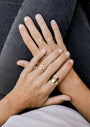 Four light-skinned hands, each wearing multiple Simple Stud Rings—18k gold plated with sparkling cubic zirconia—rest on black jeans. The person's nails are short and natural.