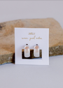 A pair of Silver Wide Hoops with a modern minimalist design and sterling silver posts, displayed on a white JaxKelly “wear good vibes” card against a neutral stone background.