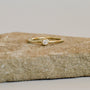 The Simple Stud Ring features a single round diamond in a bezel setting on an 18k gold plated band, shown atop a rough beige stone with a neutral background.