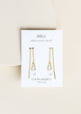 A pair of JaxKelly Gemstone Threader - Clear Quartz earrings with clear quartz crystal pendants is displayed on a white card reading "JaxKelly," "Wear Good Vibes," and "Clear Quartz Cleansing" against a neutral background.