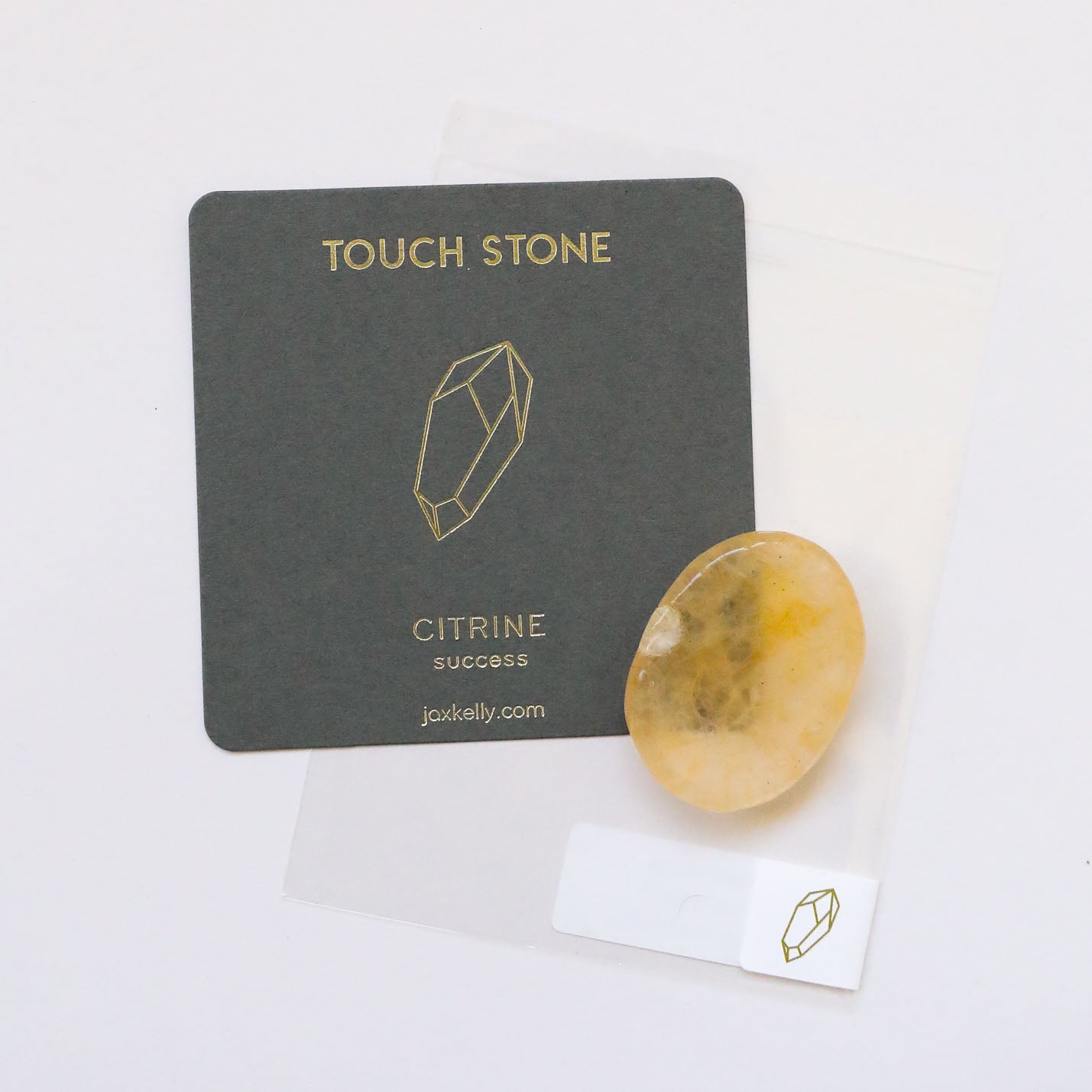 A Citrine Touch Stone rests beside a dark gray card labeled "Touch Stone" with a gold gemstone outline, the phrase "Citrine Success," and a small website link, all displayed on a white background.