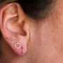 A close-up of an ear wearing the Minimalist Bar earring—an 18k gold-plated slim bar—on the lobe, alongside a hexagon-shaped hoop and a curved open hoop, all in gold.
