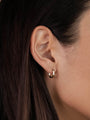 Close-up of a woman's ear with straight brown hair, wearing the Small Rectangular Hoop earring. The shiny gold hoop has sterling silver posts. Her skin looks smooth and the softly blurred background adds a gentle touch.