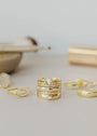 The Inset Baguette Ring, along with elegant stacking rings featuring gemstones and intricate designs, is beautifully arranged on a light beige surface against a softly blurred background.